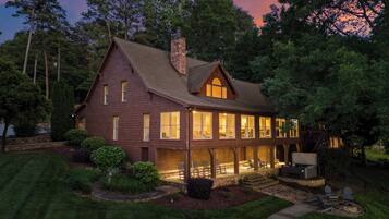 A two-story house with a wrap-around porch, a stone chimney, and a fireplace.
