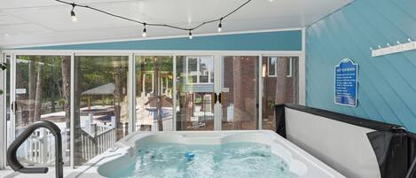 Ett bubbelbad i ett rum med stora fönster, en skylt med regler för användning av bubbelbadet och utsikt över omgivningen.