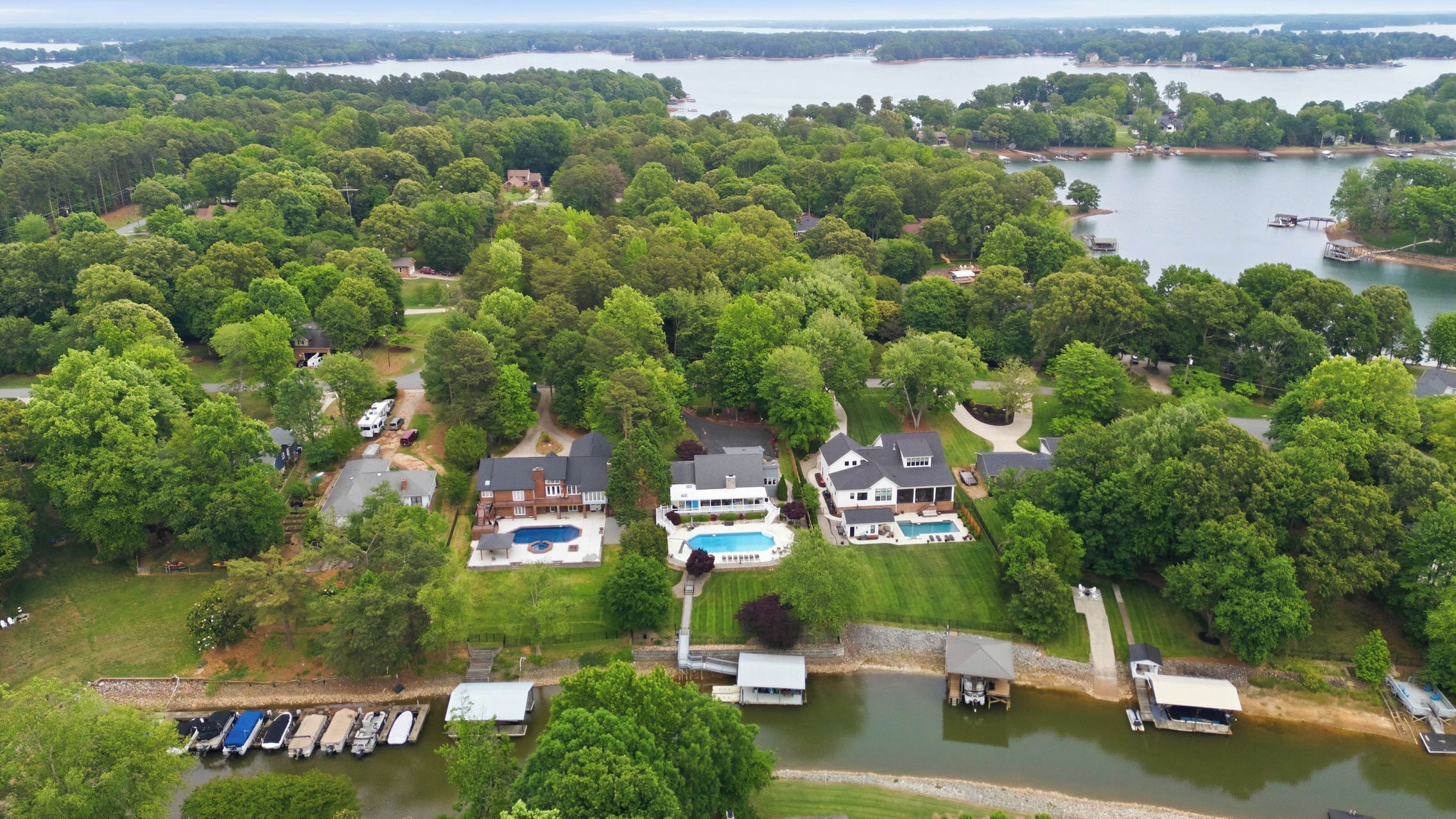 Vista aérea de una zona residencial con casas, una piscina y un muelle con barcos.