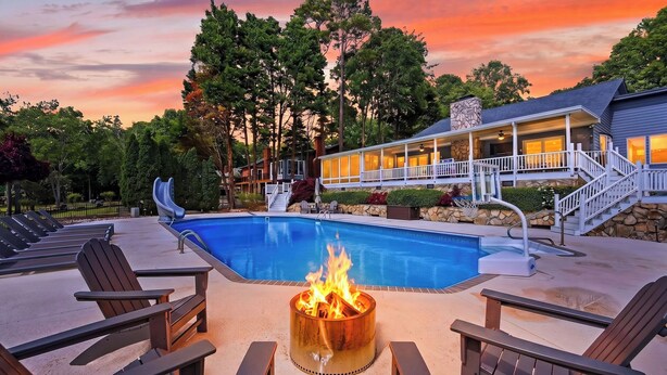 Una piscina con fuente de fuego, sillas de descanso y un edificio de fachada de piedra.
