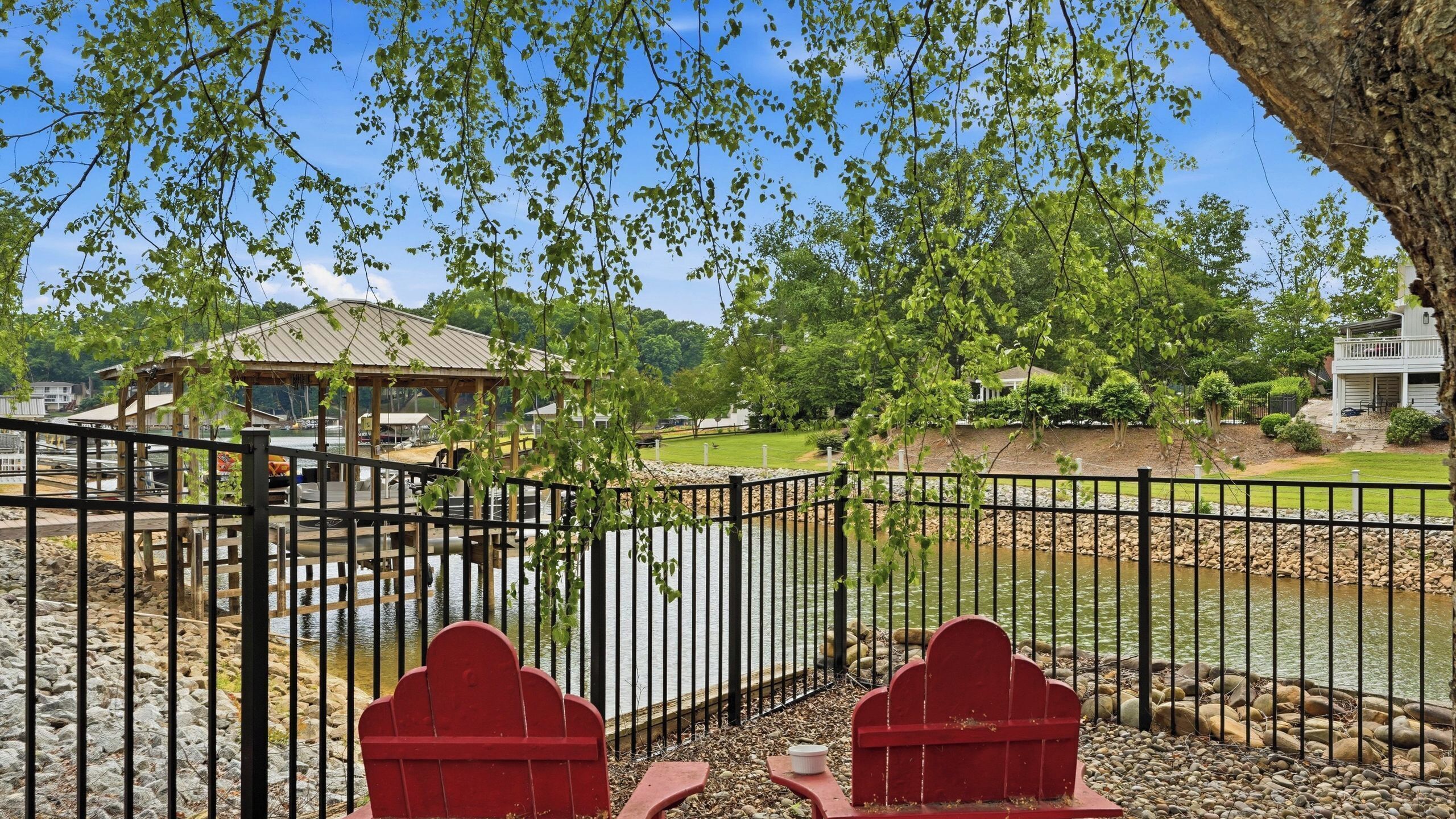 A park with a gazebo, a fenced area, and a body of water.