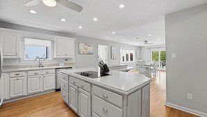 Una cocina moderna con armarios blancos, una isla central y un comedor con vistas.