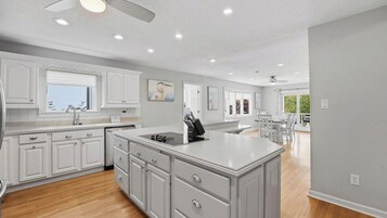Una cocina moderna con armarios blancos, una isla central y un comedor con vistas.