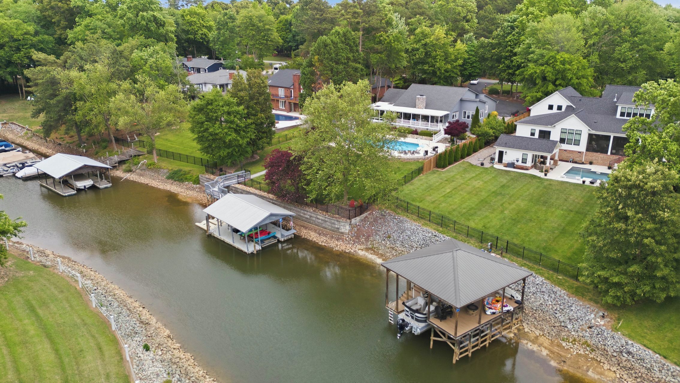 A residential area with houses, a river, docks, and a covered boat launch area.