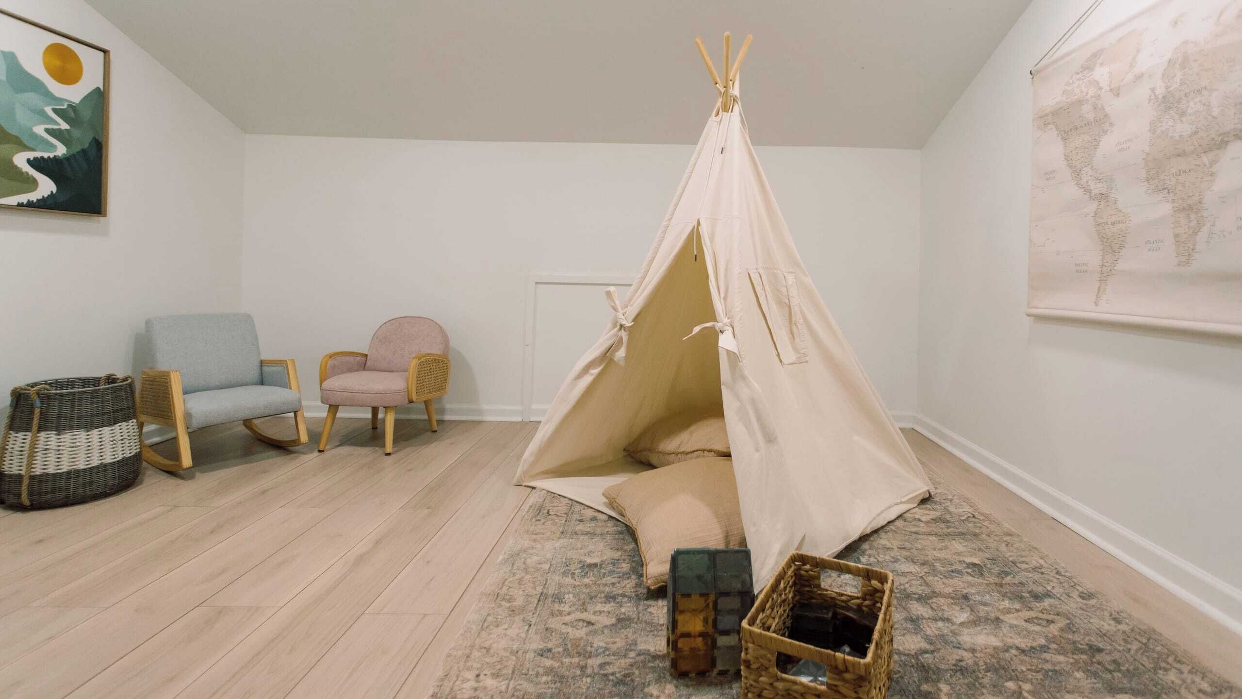 A cozy room with a beige tent, two chairs, a rug, and a map on the wall.