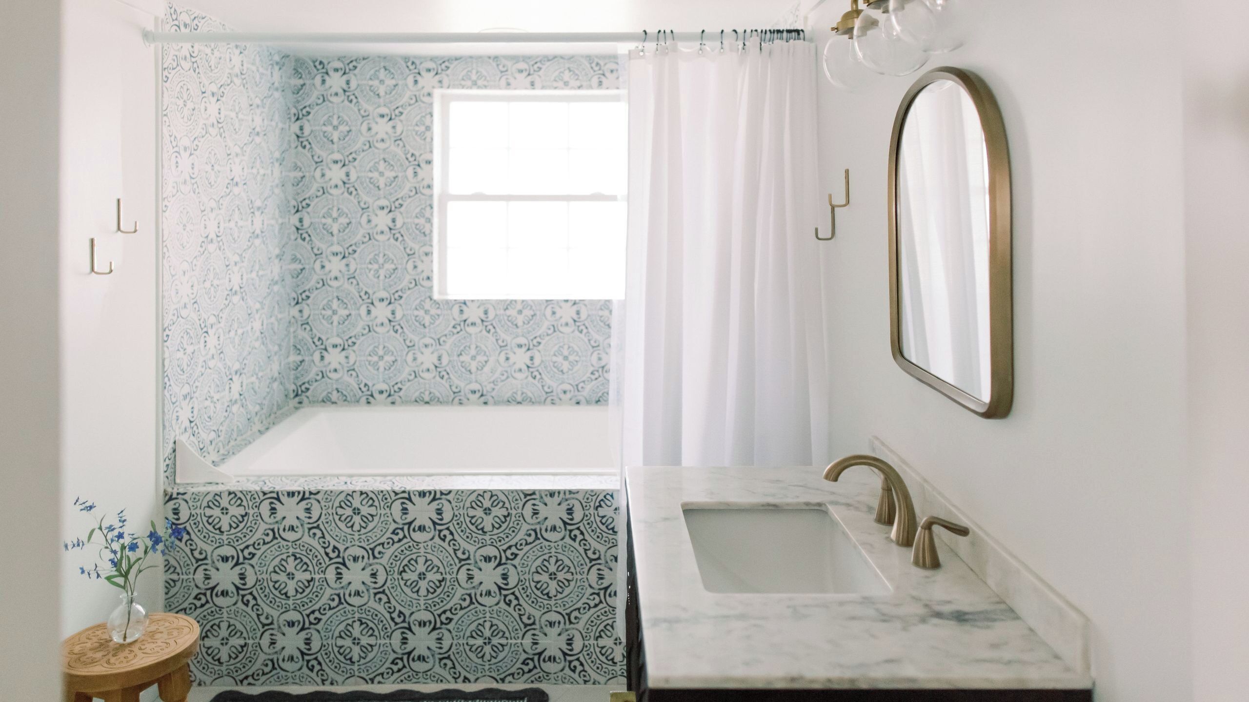 Une salle de bain avec une baignoire, un lavabo, un miroir et des carreaux décorés.