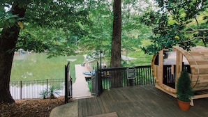 A wooden deck with a sauna cabin, a dock with boats, and a lake view. - Hummingbird Home by Avantstay Hot tub + Sauna (Statesville)