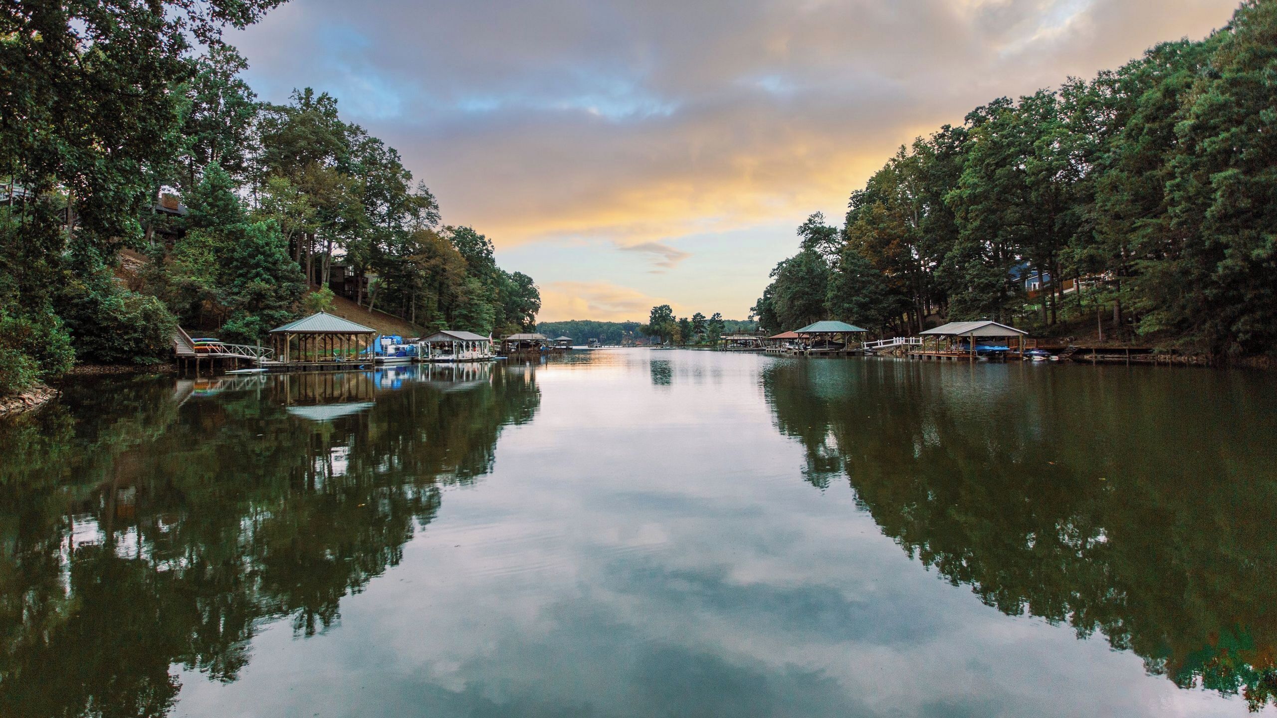 Un llac tranquil amb molls de fusta i estructures cobertes, envoltat per arbres densos.