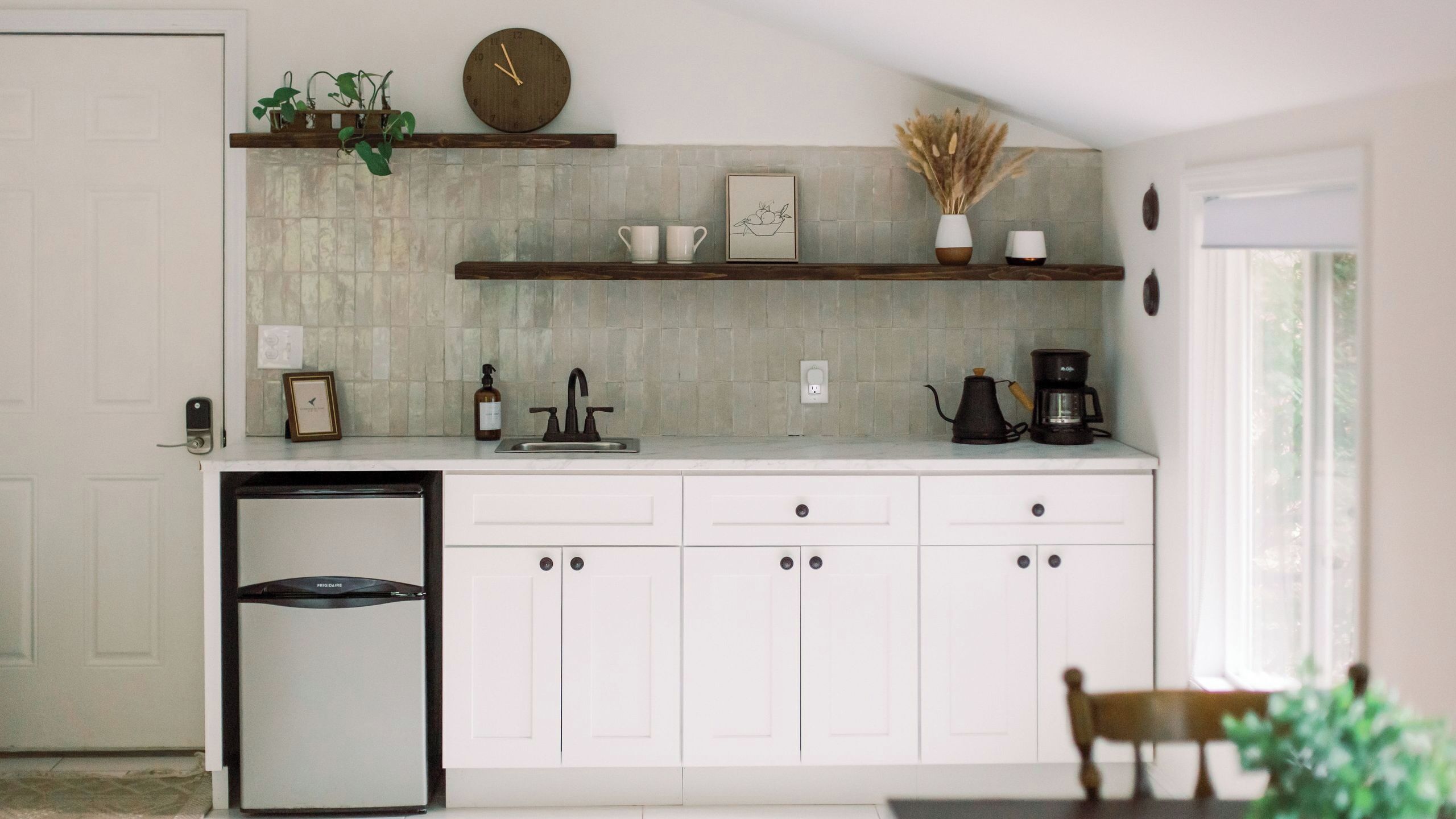 A kitchen with white cabinets, a built-in refrigerator, a sink, and a coffee maker.
