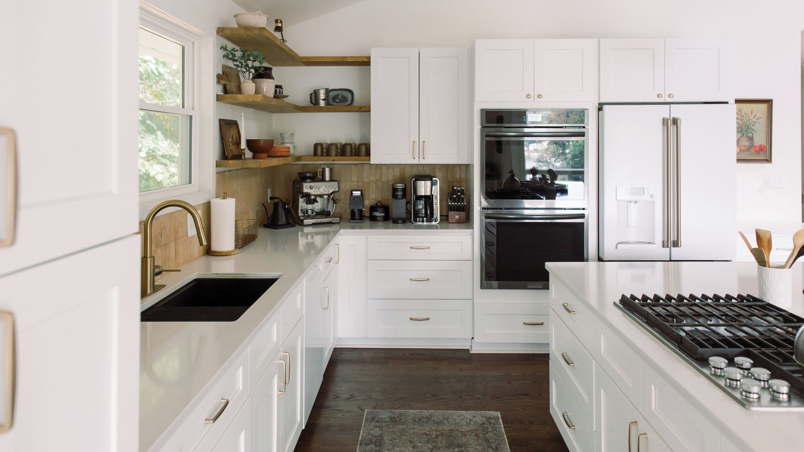 A modern kitchen with white cabinetry, stainless steel appliances, and a built-in gas stove.