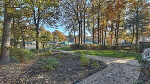 A park with a paved walkway, trees, and a body of water in the background. - Lakefront Home Private Dock, Tiki Bar, Firepit Shore to Please by Avantstay (Denver)