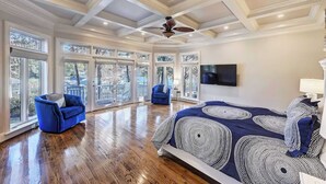 A spacious bedroom with a large bed, two blue armchairs, and a ceiling fan. - Lakefront Home Private Dock, Tiki Bar, Firepit Shore to Please by Avantstay (Denver)
