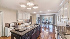 A spacious kitchen with a central island, dark cabinetry, and a dining area with a view. - Lakefront Home Private Dock, Tiki Bar, Firepit Shore to Please by Avantstay (Denver)