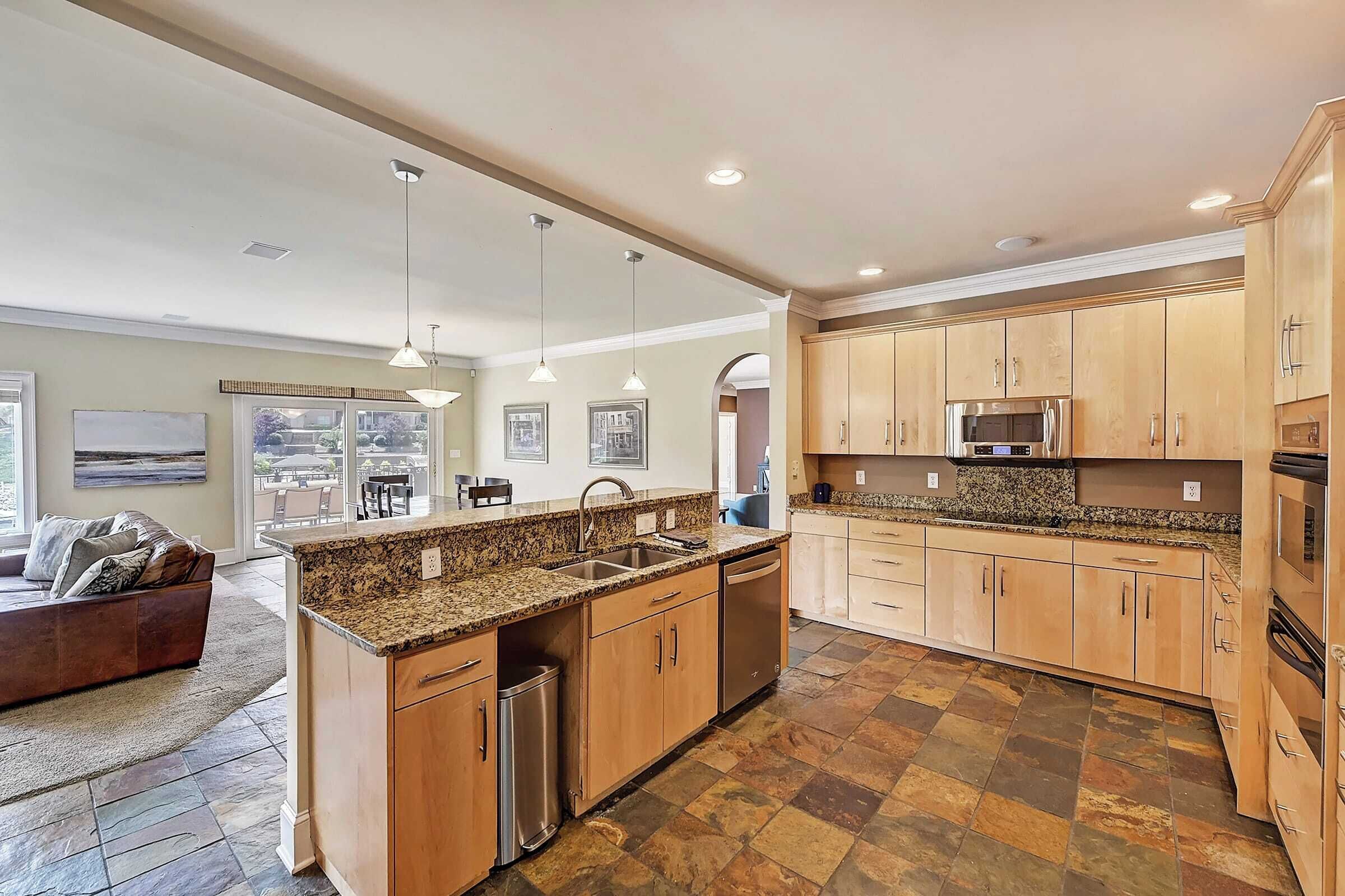 A spacious kitchen with granite countertops, wooden cabinets, and stainless steel appliances.