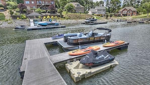 A dock with boats, a pontoon boat, and kayaks.