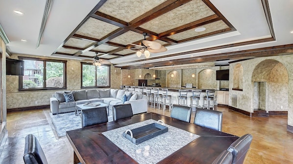 Un amplio espacio habitable con un sofá grande, una mesa de comedor y asientos de bar.