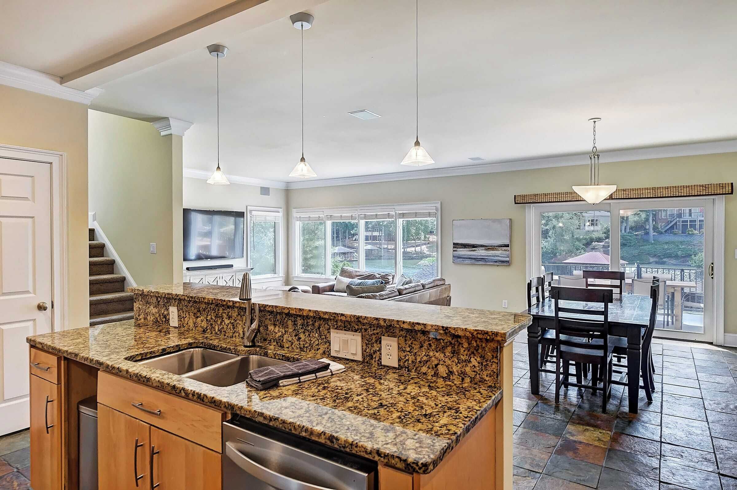 A kitchen with granite countertops, stainless steel appliances, and pendant lighting.