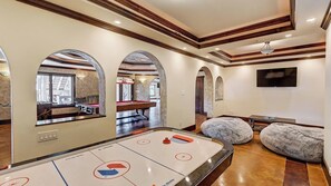 Una habitación con mesa de juego de discos, mesa de billar y televisor montado en la pared.