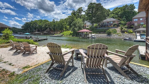 A lakeside view with Adirondack chairs, a dock, and a gazebo.