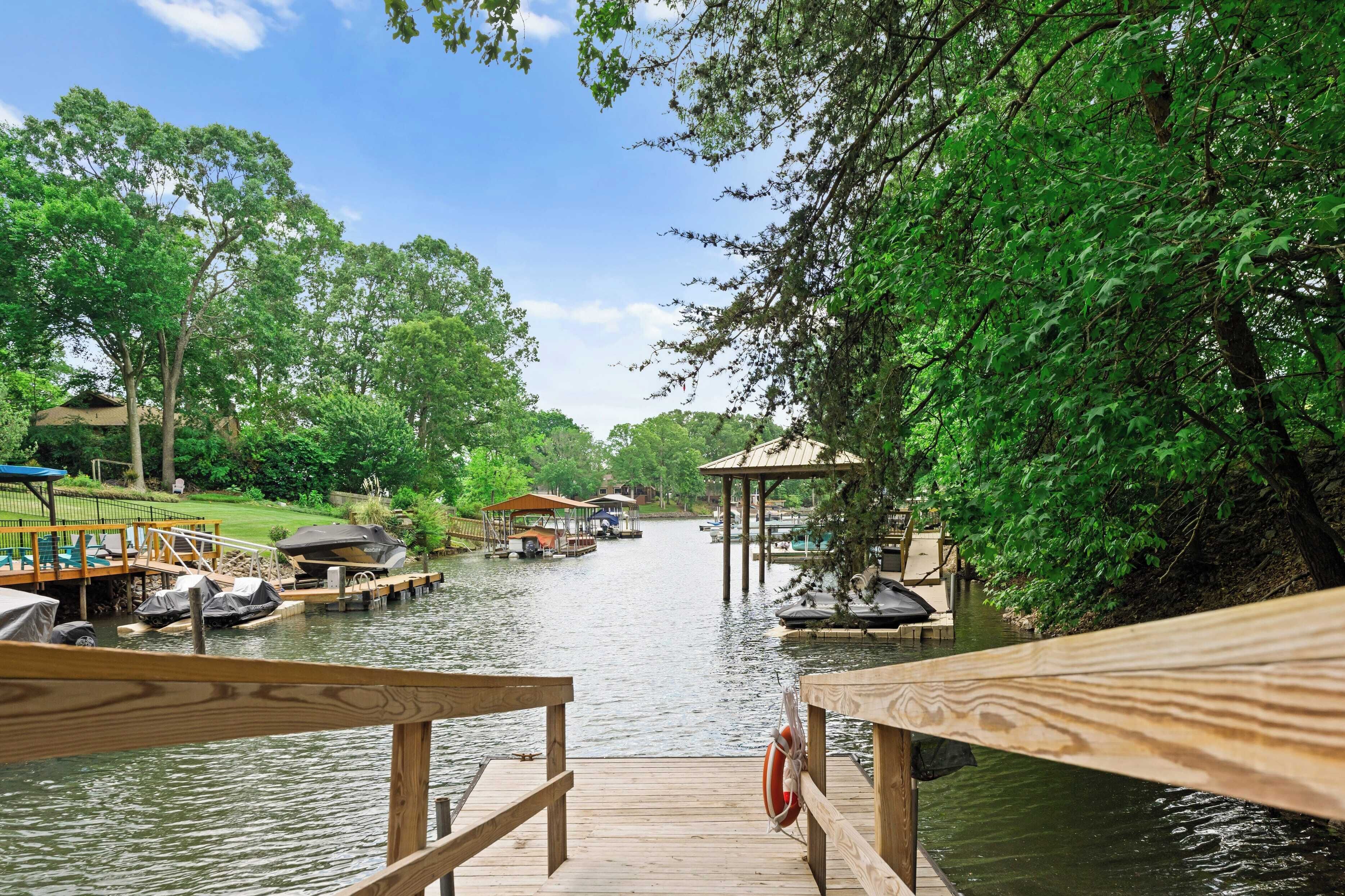 A wooden dock with a lifebuoy, a covered boat area, and a gazebo over water.