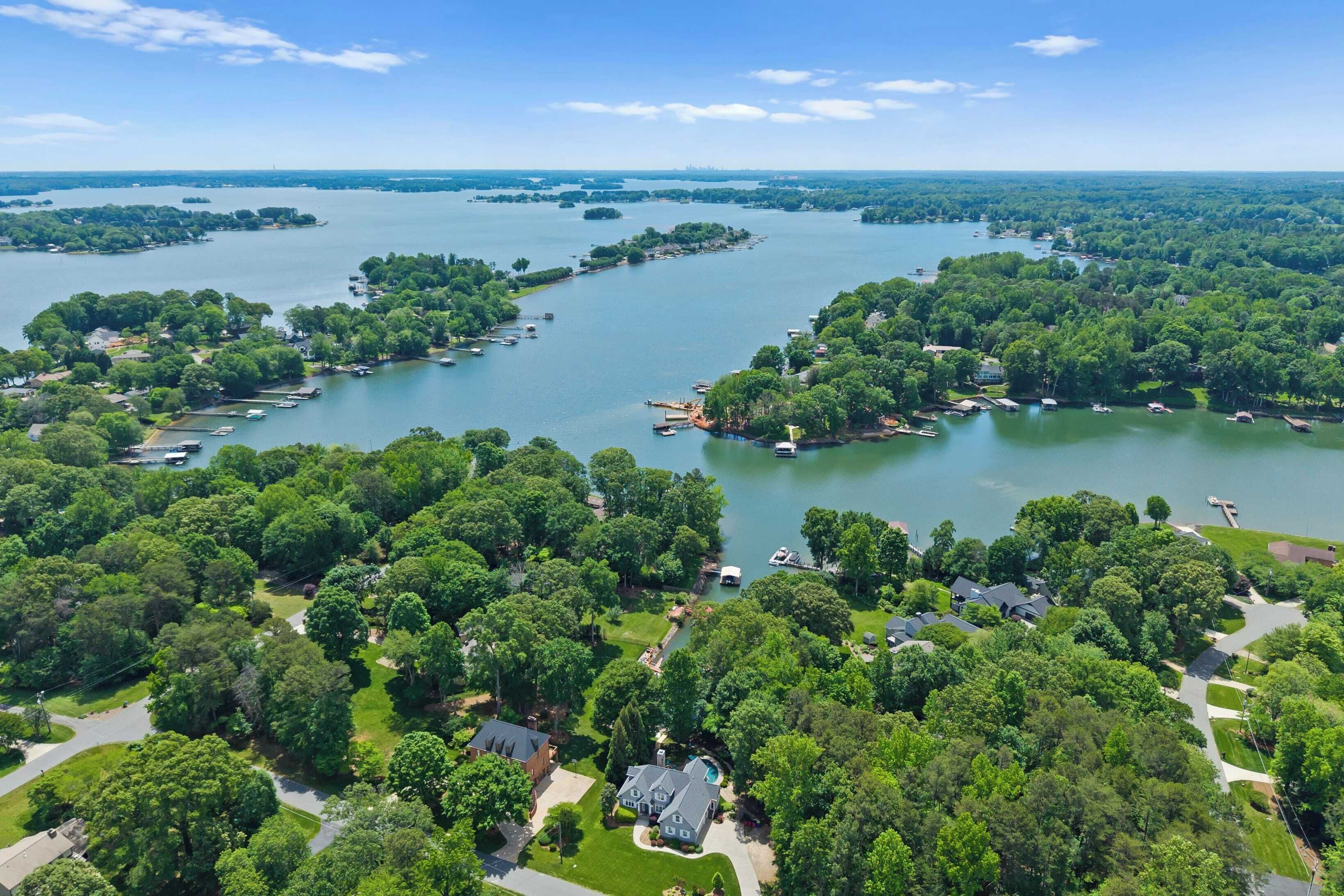 An aerial view of a lakeside residential area with multiple houses, docks, and boats.