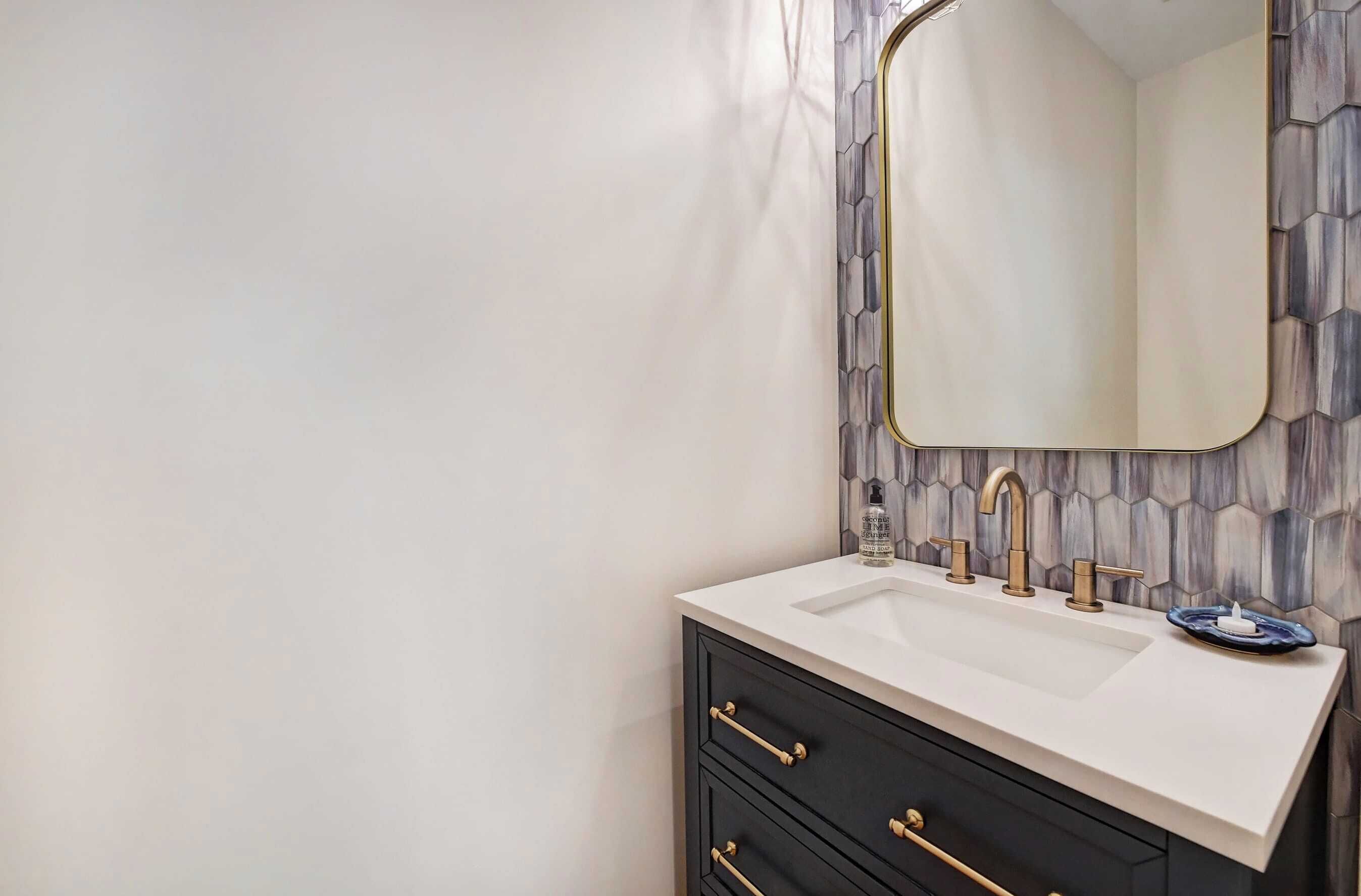 A bathroom with a white sink, gold faucets, and a mirror with a gold frame.
