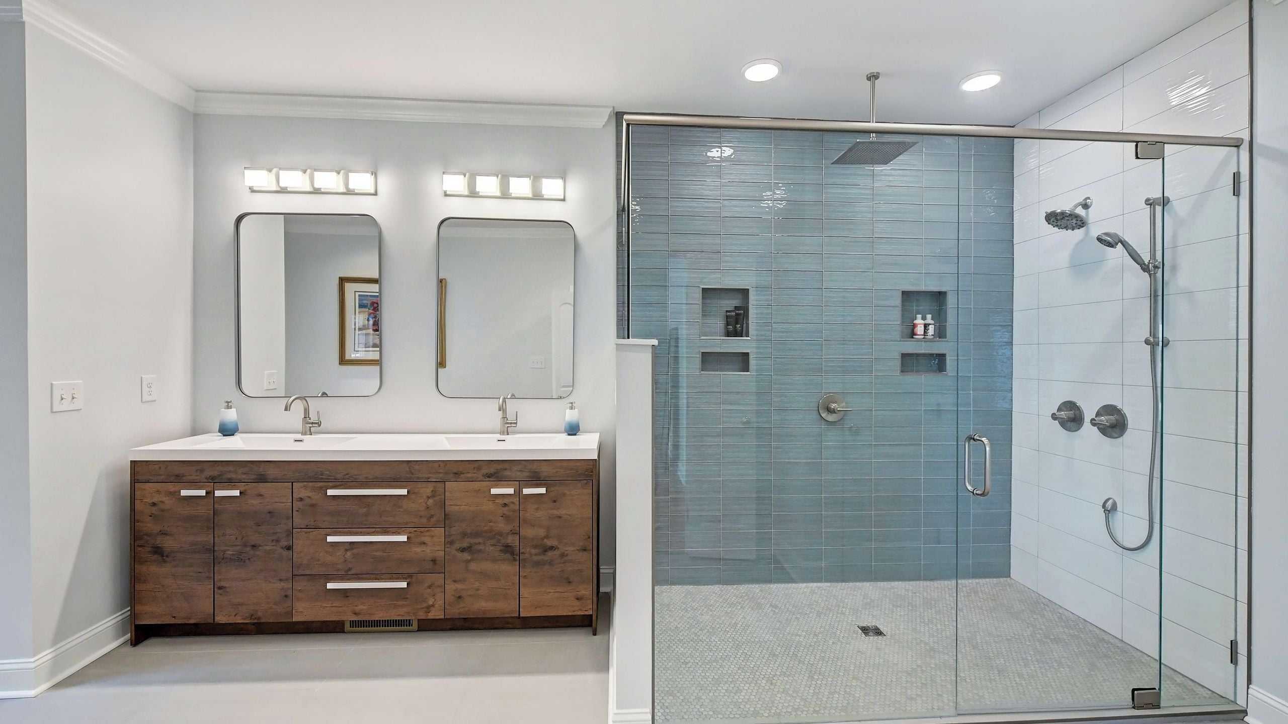 A bathroom with a glass-enclosed shower, a double vanity with wooden cabinets, and two wall-mounted mirrors.