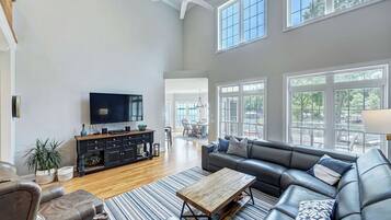 A spacious living room with a large TV, leather sofa, and a wooden coffee table.