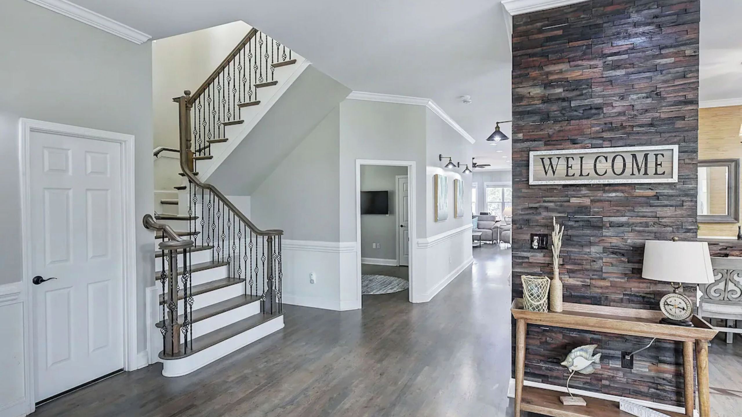 Un intérieur moderne avec un escalier, un panneau d’accueil et un mur d’accent en pierre.