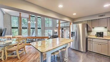 Una cocina moderna con una isla grande, electrodomésticos de acero inoxidable y ventanas amplias que ofrecen vistas al exterior.