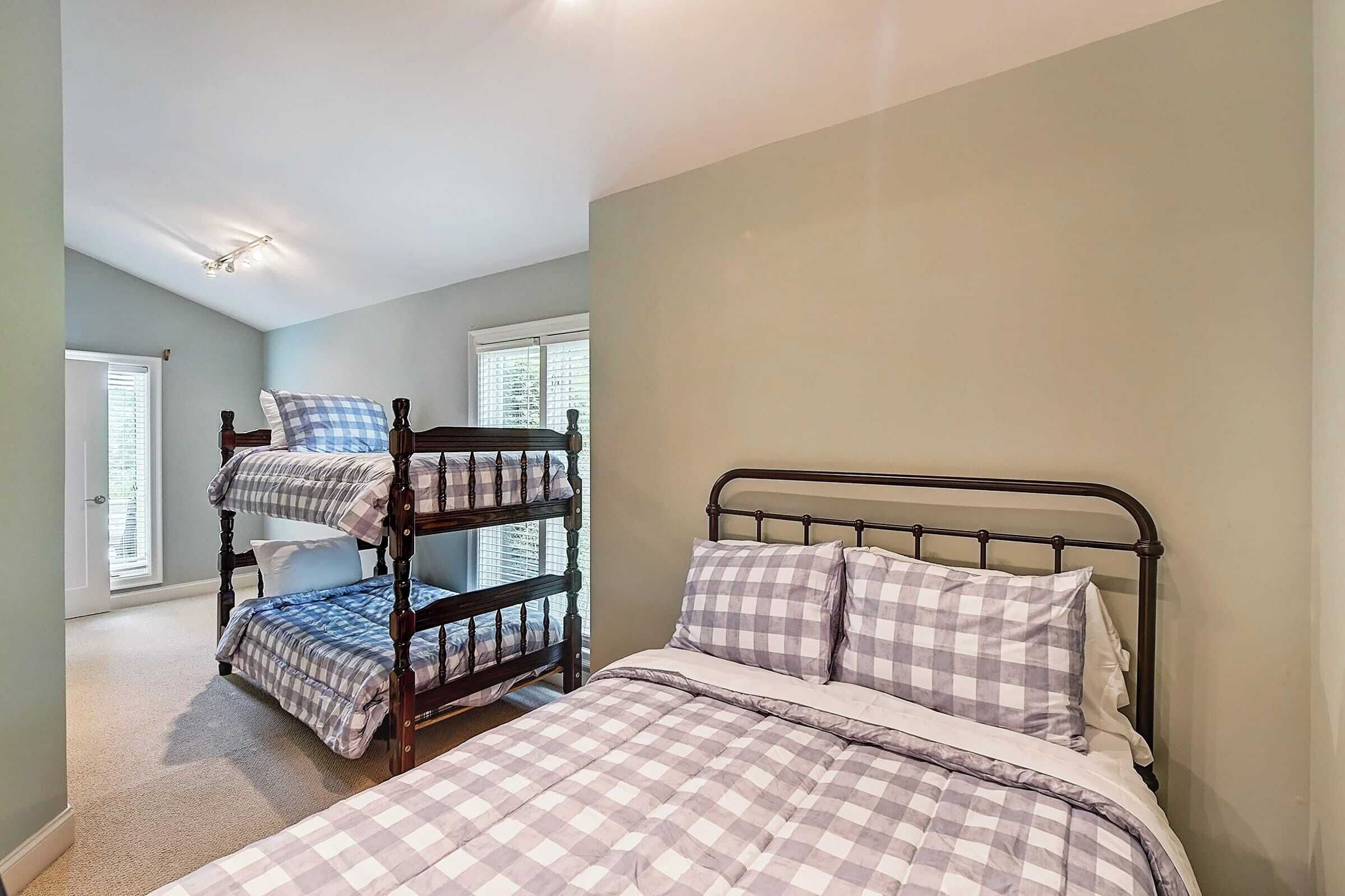 A bedroom with a bunk bed and a single bed, both with checkered bedding.