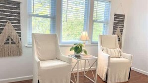 A room with two white armchairs, a small table, and a lamp. - Golf Cart Private pool Bay and Beach Access Pet Friendly (St. George Island)
