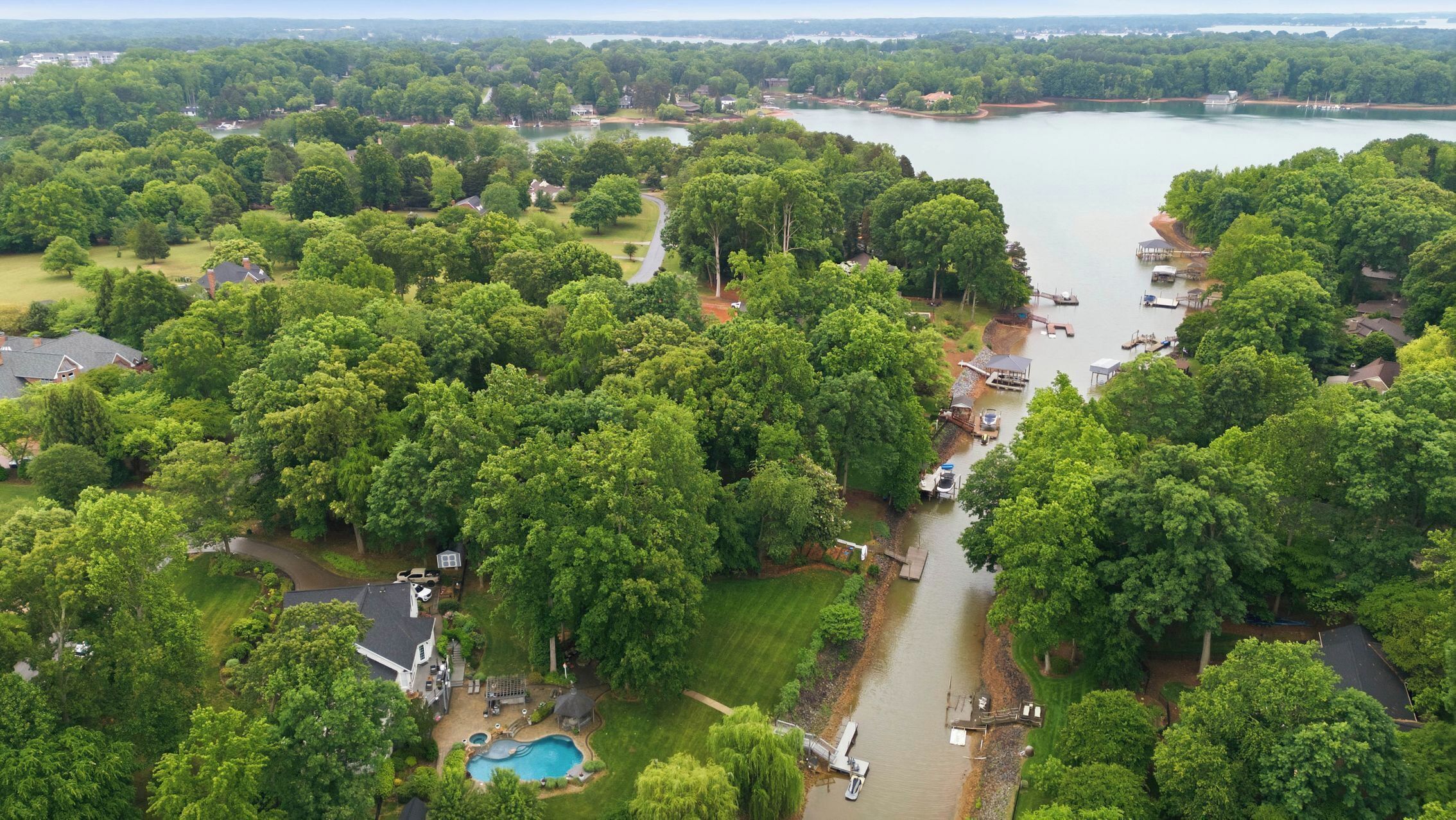 Vista aérea de una zona residencial con un lago, piscina y barcos amarrados.