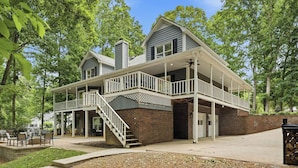 A two-story house with a covered patio, brick exterior, and a staircase leading to an upper level. - Porch Paradise by Avantstay New Pool, Firepit (Mooresville)