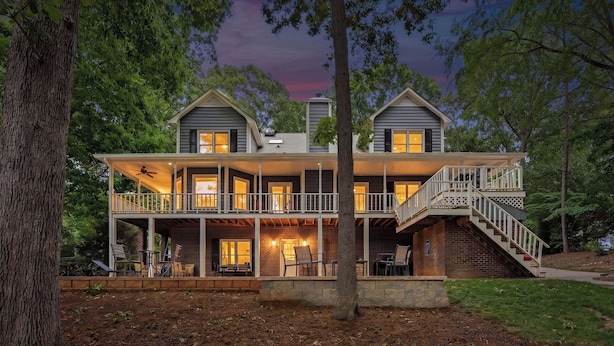 A two-story house with a balcony, a staircase, and a porch with outdoor seating. - Porch Paradise by Avantstay New Pool, Firepit (Mooresville)
