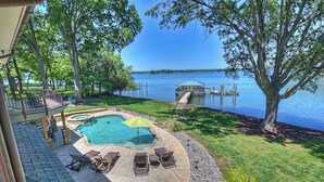 Un jardin avec une piscine, des chaises longues et une jetée qui s’avance dans un lac.