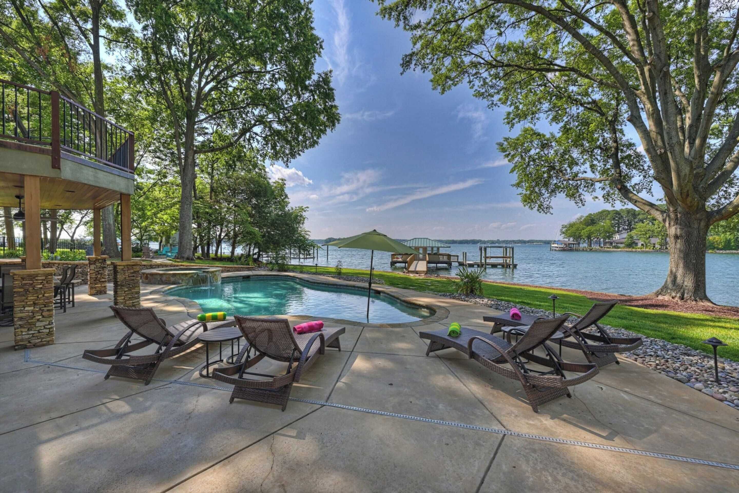 A poolside area with lounge chairs and a view of a lake.