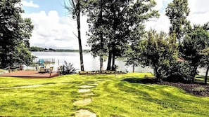A grassy area with a dock and chairs by a lake. - Flip Flop Therapy by Avantstay Lakefront Home w/ Game Room & Dock Access (Mooresville)