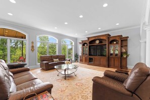 A spacious living room with leather sofas, a glass coffee table, and a wooden entertainment center.