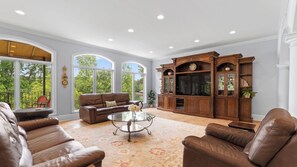 A spacious living room with leather sofas, a glass coffee table, and a wooden entertainment center.