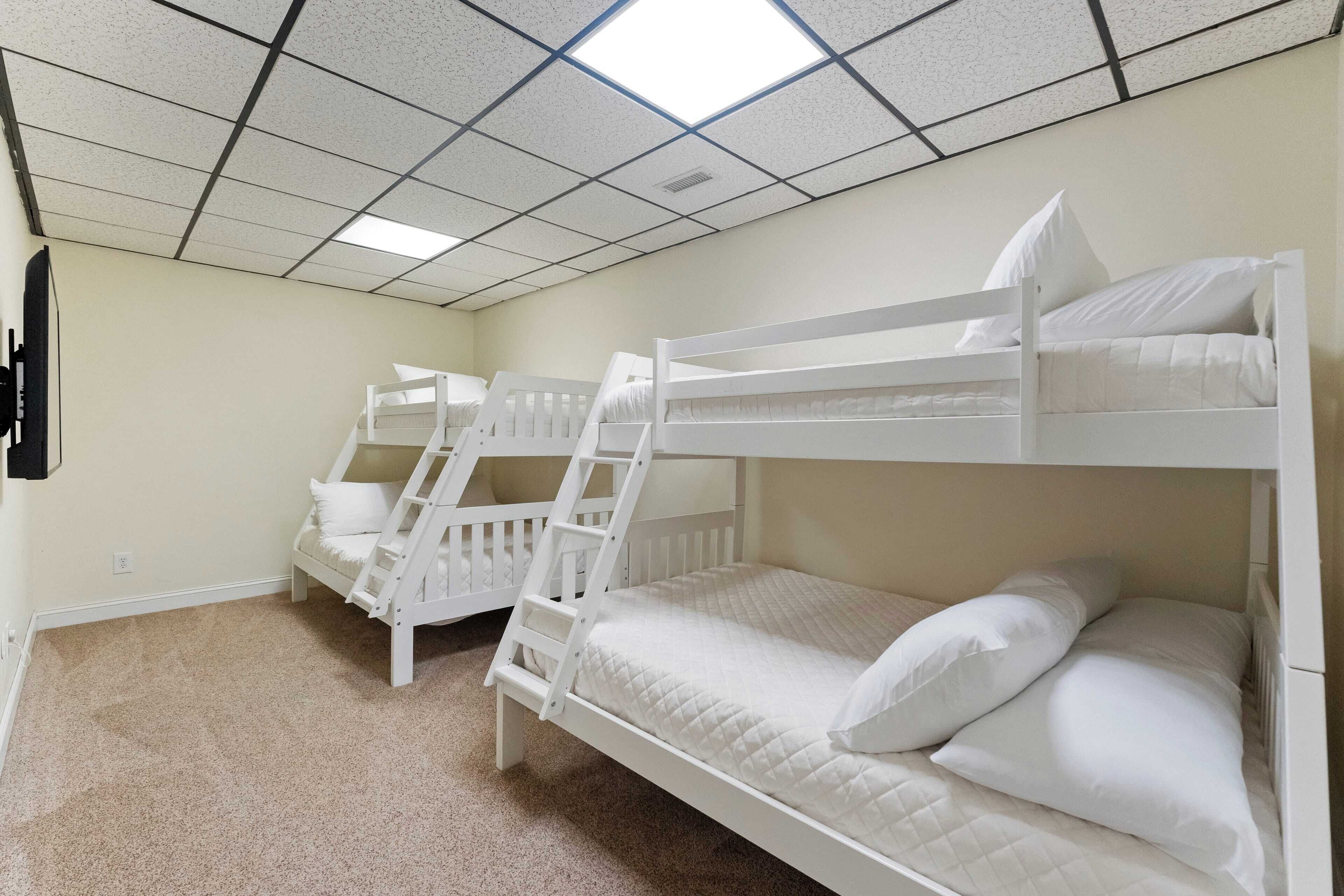 Een slaapkamer met stapelbed, vloerbedekking en een plafond met vierkante tegels.