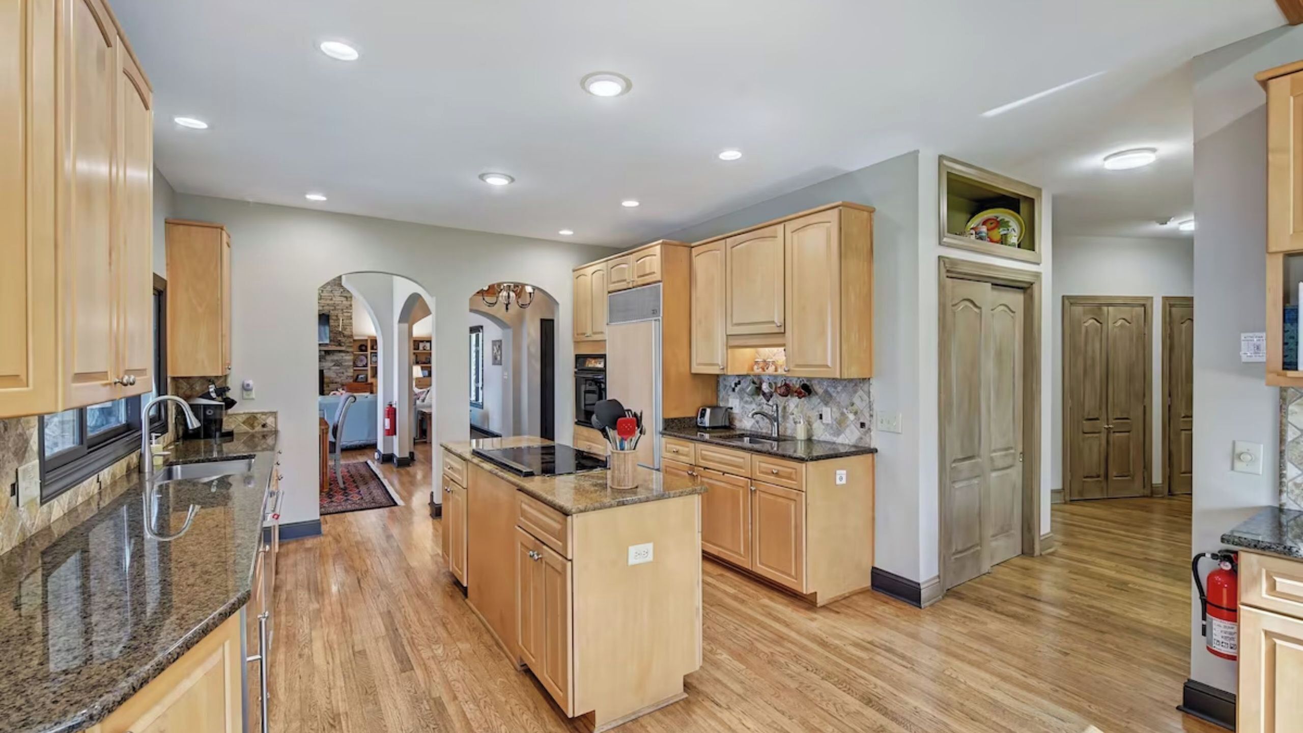 A spacious kitchen with wooden cabinets, granite countertops, and a central island.