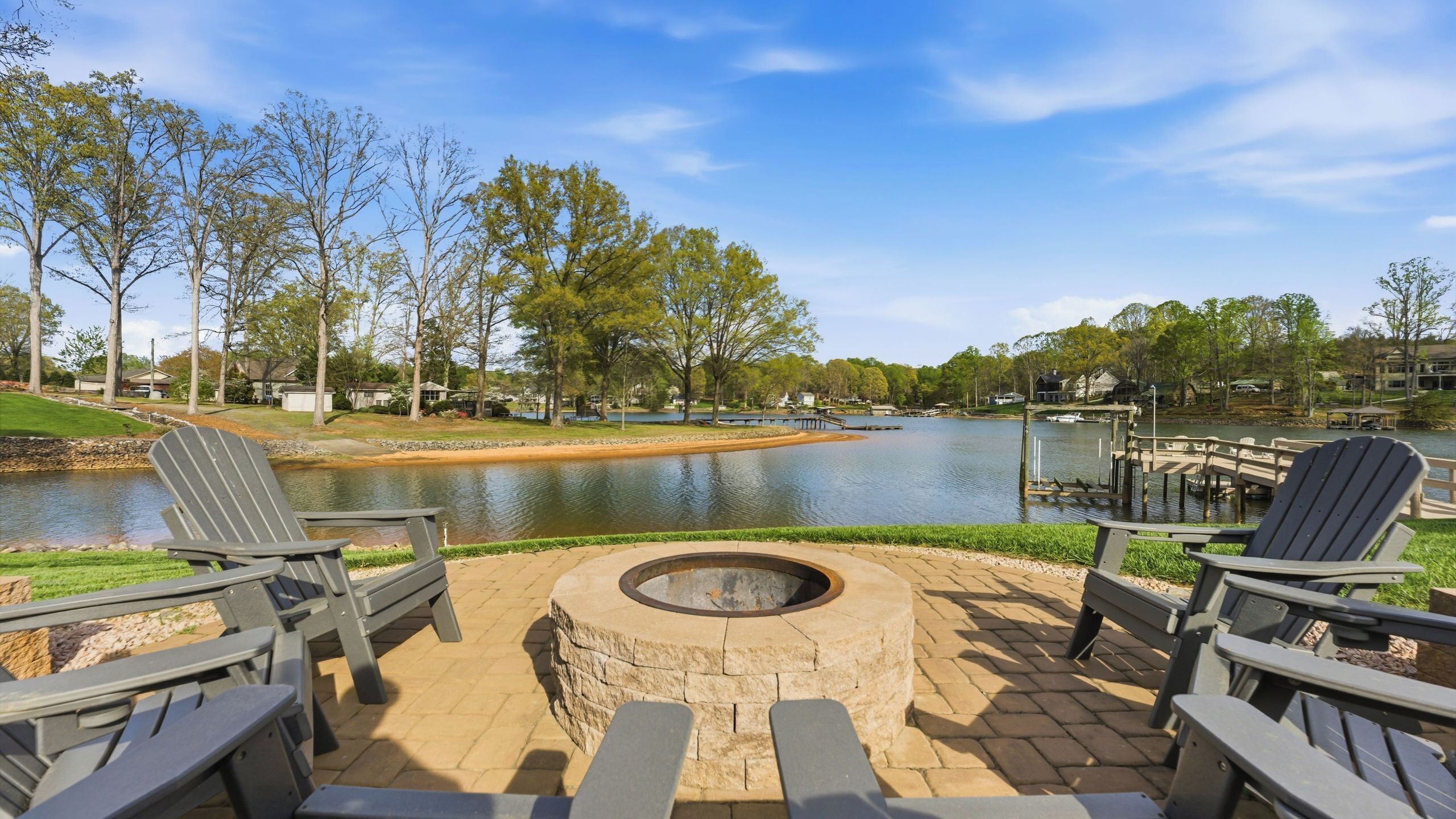 Une terrasse au bord du lac, avec des fauteuils Adirondack, un foyer et un quai.