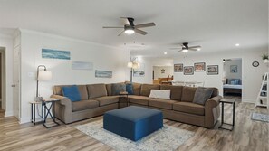 A living room with a sectional sofa, a coffee table, a floor lamp, and ceiling fans. - Kool Breeze by Avantstay Boat Ramp + Hot Tub (Denver)