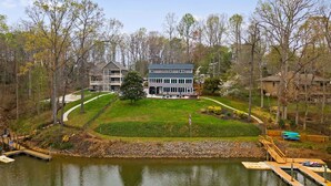 A lakeside property with a large house, a dock, and a well-maintained lawn.