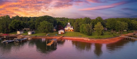 A lakeside property with a main house, smaller buildings, and docked boats.
