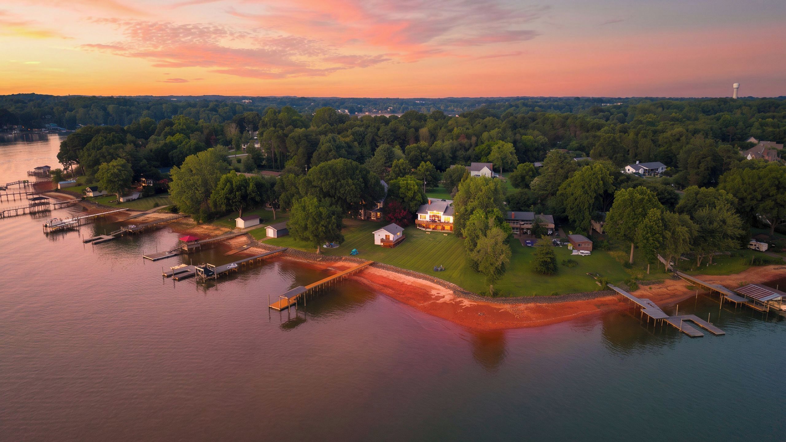 An aerial view of a lakeside property with docks, houses, and a docked boat.