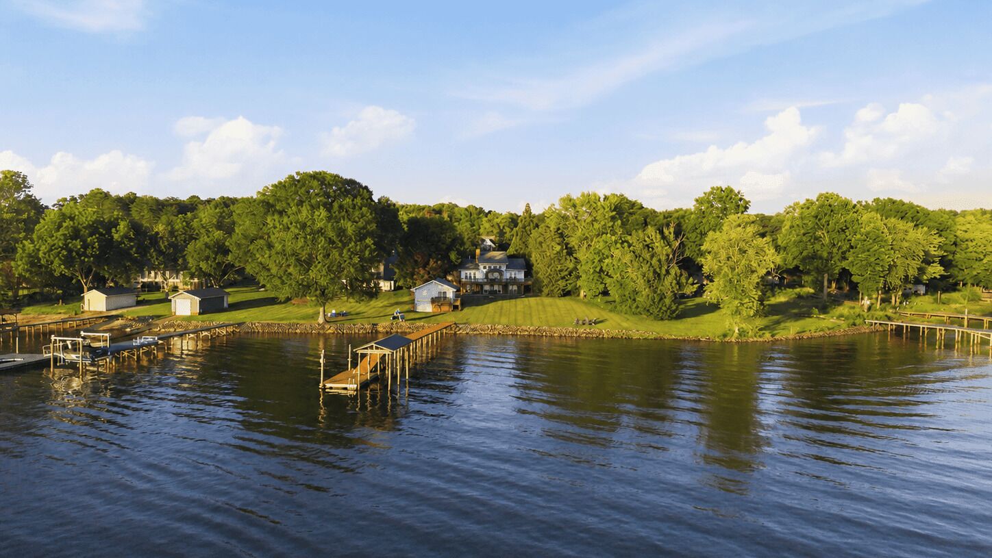 A lakeside property with a dock, a large house, and a small shed.