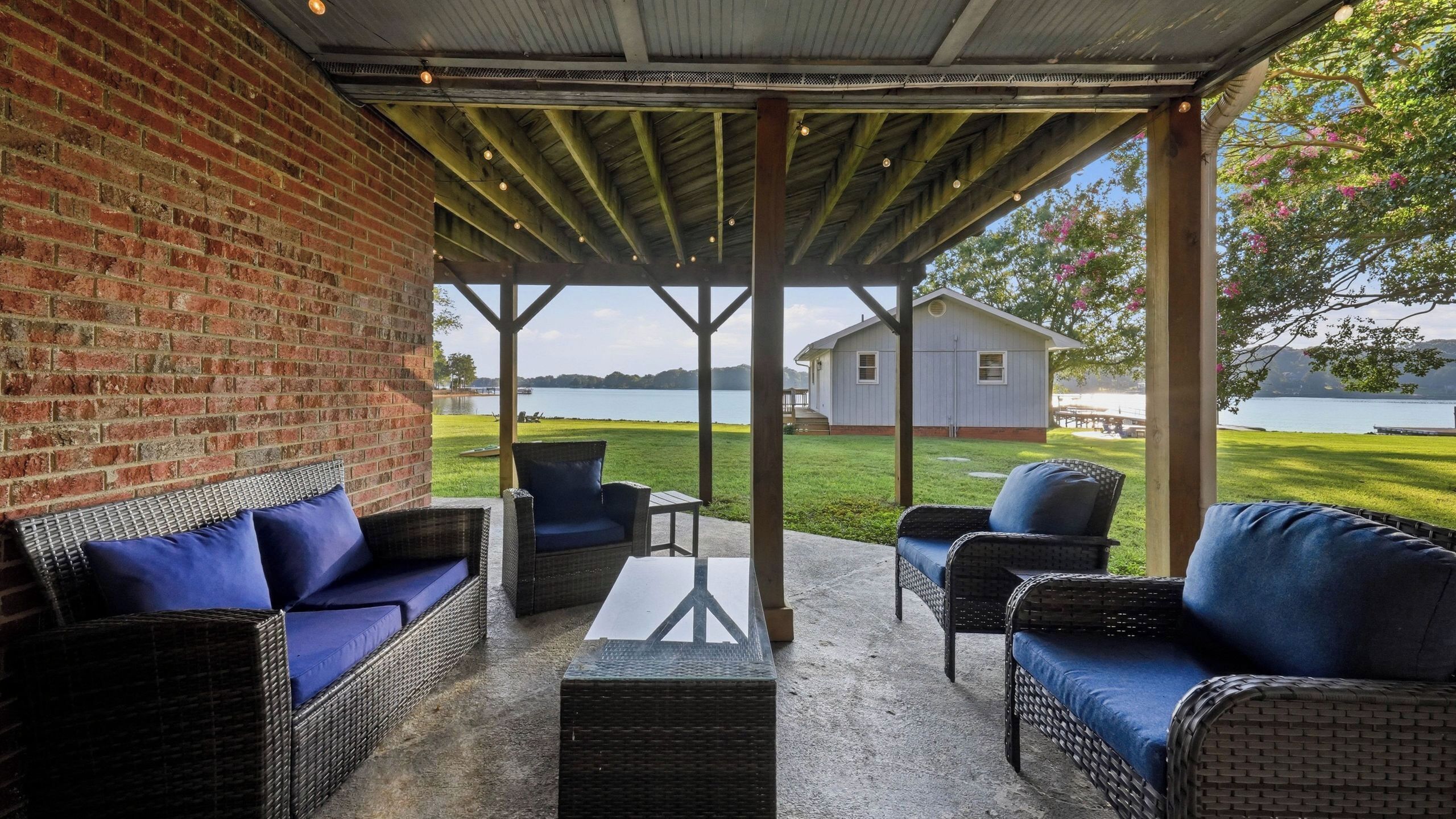 A covered patio with wicker furniture and a view of a lake.