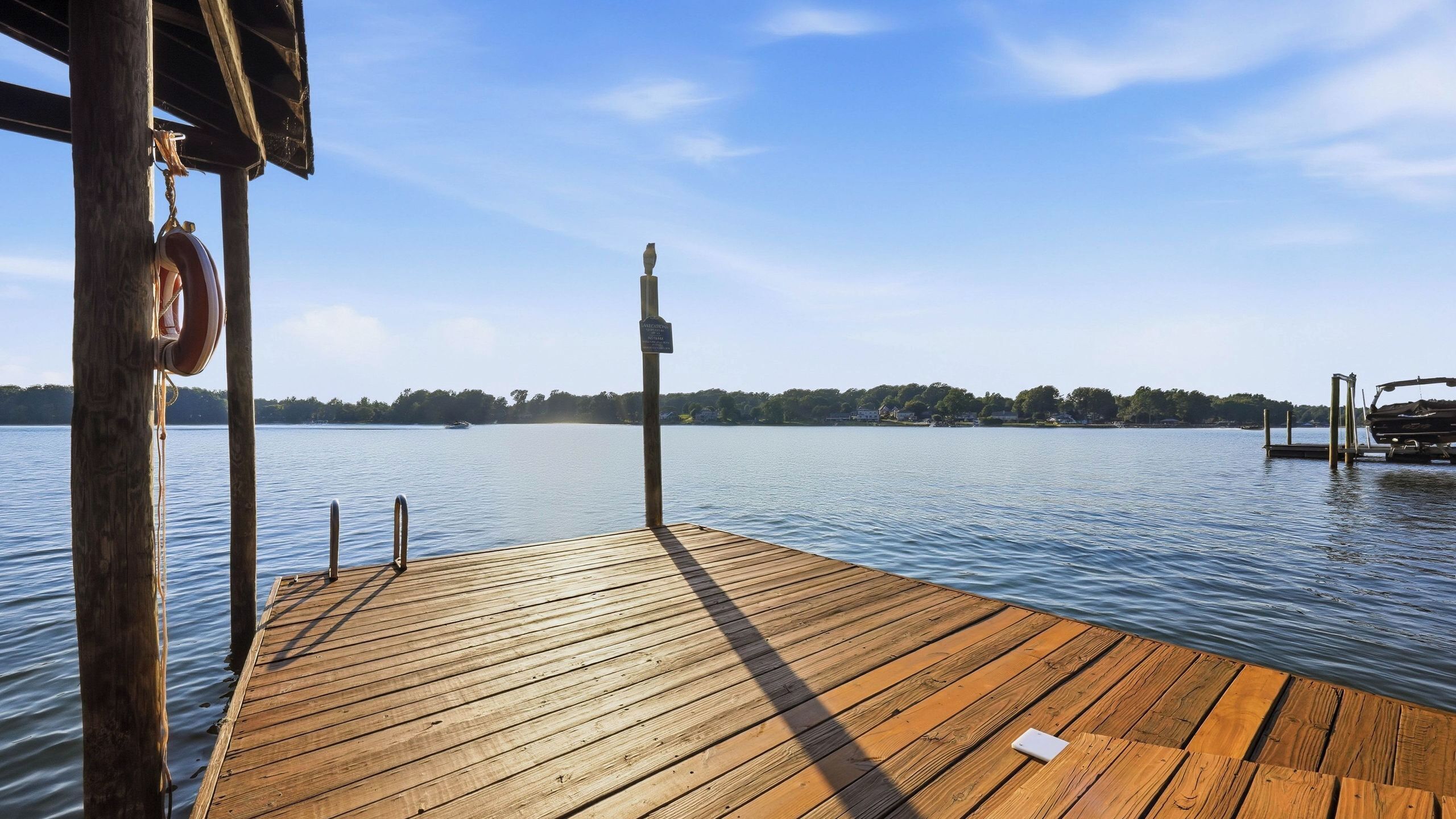 A wooden dock extending into calm water with a clear sky above.